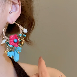 Detail of bohemian hoop earring with red flower, turquoise cactus and small white shell