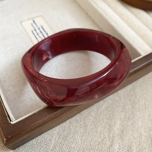 Detail of a dark red marbled acrylic bracelet with a vintage rounded square design