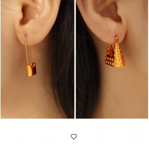Macro detail of gold-tone safety pin earring and embossed triangle purse stud jewelry