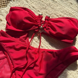 Détail du bikini bustier rouge avec anneau métallique doré sur le haut texturé