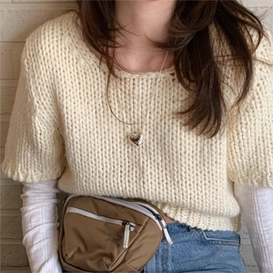 Detail of a minimalist 925 silver heart necklace layered over a knit sweater