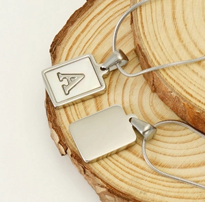 Macro detail of silver rectangular letter A pendant with shell inlay on a wooden base