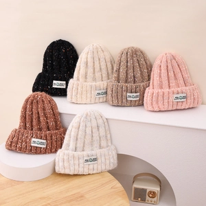 Detail showing various colors of knitted hats with colorful dots and letter patches