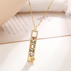 Close-up of gold MOM pendant with colorful zircon heart and floral engraving details