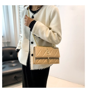 Detail of beige quilted shoulder bag with gold tassel, metal logo and chain strap