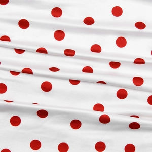 Close-up of soft white fabric with red polka dots and smooth satin texture on dress
