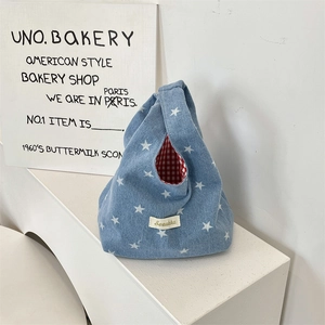 Detail of a denim tote with white stars, red checkered lining and woven Sezakka label