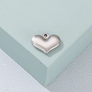 Minimalist silver titanium steel 3D heart pendant on light green geometric stand