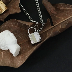 Detail of industrial silver padlock pendant with screw motifs on chunky curb chain