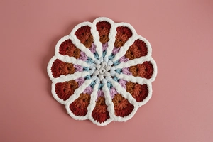 Close-up of hand-knitted colorful petal-shaped coaster with detailed crochet textures
