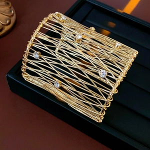Detailed view of gold mesh woven cuff bracelet with sparkling crystal accents on black stand