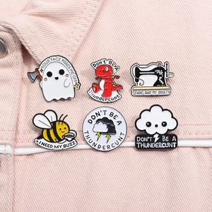 Set of 6 creative enamel pins featuring ghosts and bees on pink denim fabric surface
