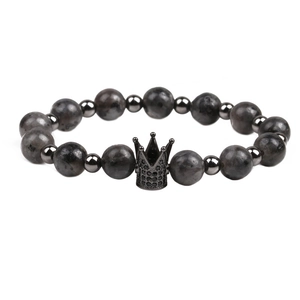 Detailed close-up of 8mm tiger eye stone beads with a black crown charm on the bracelet