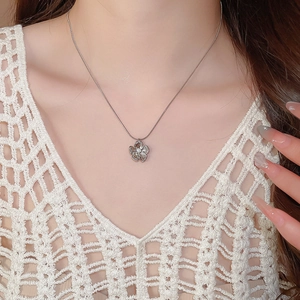 Detail of silver stainless steel flower pendant necklace with crystals on model collarbone