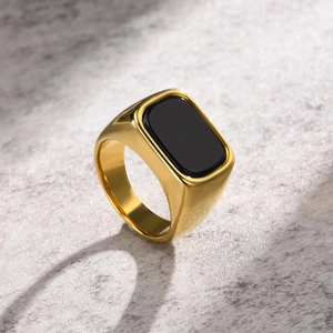 Detailed view of a gold-plated stainless steel signet ring with a black square gemstone inlay