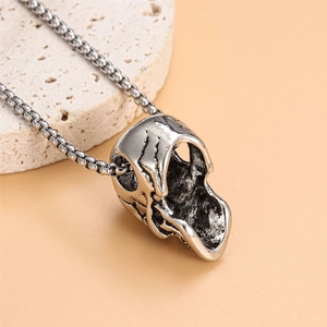 Macro shot of vintage silver skull pendant on box chain with punk metal texture details