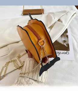 Detail of yellow bat-shaped Halloween shoulder bag with golden chain strap and leather finish