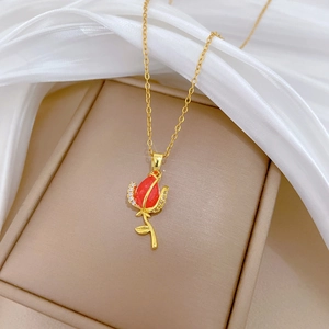 Detailed macro view of a gold-plated tulip pendant necklace with red petals and diamonds