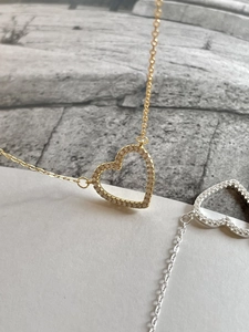 Macro detail of gold and silver heart necklaces featuring sparkling white zircon stones