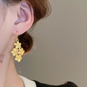 Close-up of matte gold flower earrings with a delicate brushed finish and textured petals