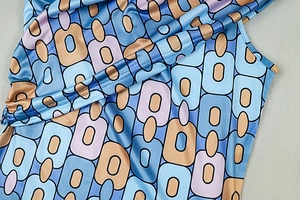 Detail of geometric chain print on satin fabric with light blue and lilac tones
