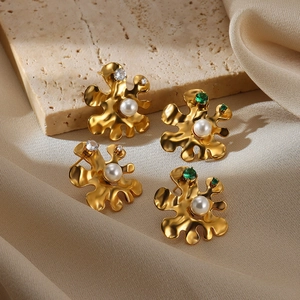 Detail of gold-plated flower earrings with white pearls and zircons on a stone surface