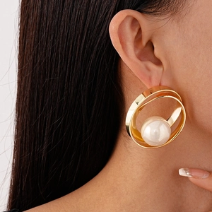 Gros plan de boucles d'oreilles dorées géométriques à double cercle avec perle