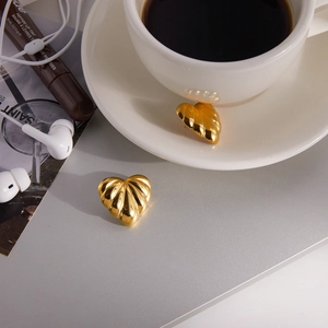 Detail of 18k gold heart earrings with radial textured shell pattern on a grey table