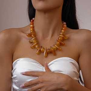 Close-up of amber acrylic teardrop beads necklace on a model with warm resin luster