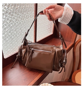 Détail du sac sous le bras marron foncé brillant avec de multiples poches zippées fonctionnelles