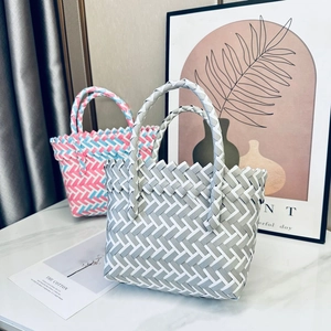 Handwoven basket bags in grey-white and pink-blue-white colors on marble surface