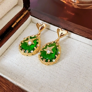 Detail of vintage gold earrings with green water drop gems and white pearls on wood box