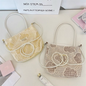 Détail du sac en toile avec broderie de roses en dentelle et chaîne de perles