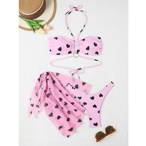 Détail du haut de bikini rose à pois avec une boucle métallique en forme de cœur sur la poitrine