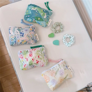 Close-up of four floral cotton pouches with zippers, hand straps and woven brand labels