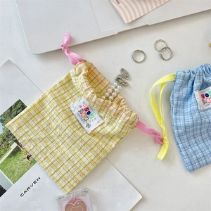 Detailed close-up of yellow and blue plaid cotton drawstring bags with colorful woven labels