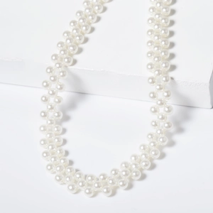 Close-up of double-layered faux pearl necklace draped on a white geometric block