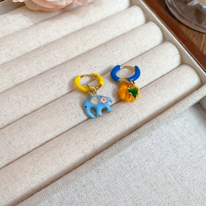 Detail of colorful enamel pumpkin and elephant charms on elegant gold hoop earrings
