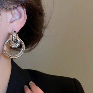 Close-up of polished silver multi-hoop earrings worn by a model in a black suit