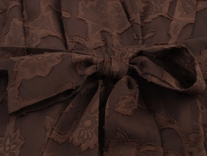 Détail macro du tissu jacquard floral marron foncé avec un nœud de ceinture élégant
