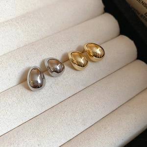 Macro view of gold and silver teardrop earrings on a velvet jewelry display tray