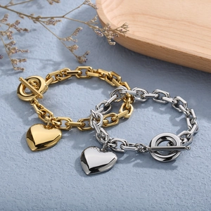 Detailed view of gold and silver heart pendant bracelets with toggle clasp on blue surface
