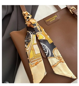 Nahaufnahme einer braunen Leder-Tragetasche mit dekorativem bedrucktem Seidenschal-Detail