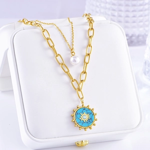 Detailed shot of double-layer gold necklace featuring turquoise sun and pearl pendants