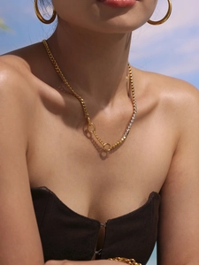 Detail of double-layer stainless steel bear necklace and textured hoop earrings on model