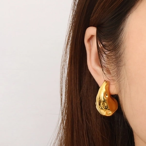 Gros plan sur les boucles d'oreilles goutte en or 18 carats au design de métal liquide poli