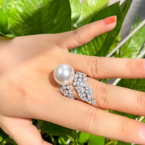 Close-up of a luxury French style pearl ring with sparkling pavé diamonds on a hand