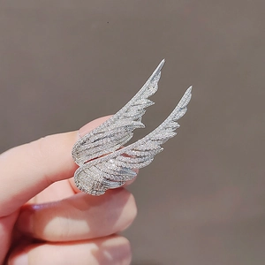 Elegant silver wing brooch featuring shimmering inlaid crystals in a handheld view