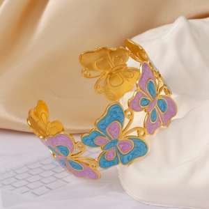 Detail of a gold butterfly bracelet with blue and purple enamel on a white stone base