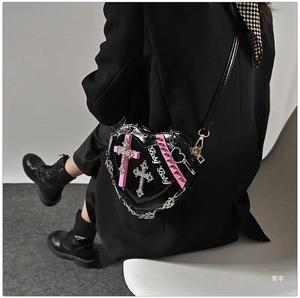 Detail of black heart bag featuring pink cross, silver chains and Baby Baby text